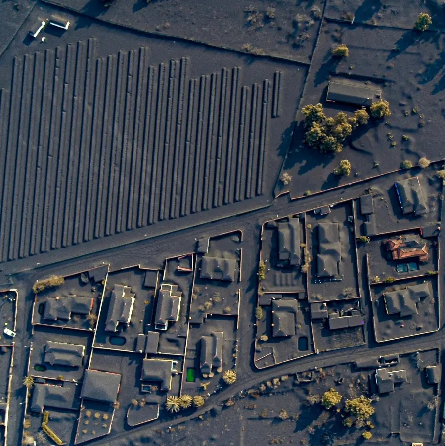 Vista aérea cenital de un caserío y sus plantaciones cubiertos por completo de ceniza volcánica
