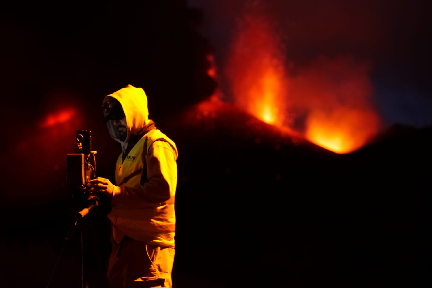 Operador de Dron Services Canarias de noche, con la erupción volcánica de La Palma al fondo